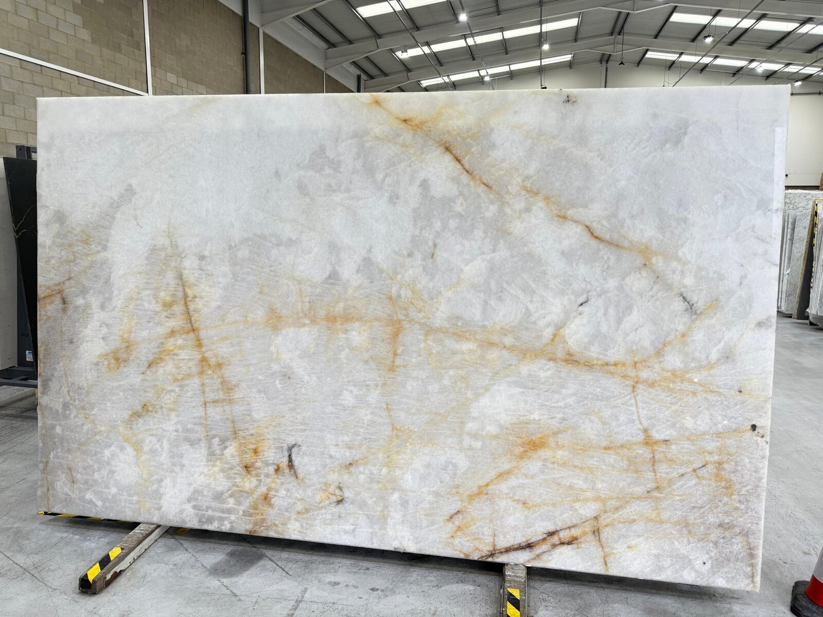 Cristallo Quartzite slab with icy translucent white background and golden amber iron-oxide veining