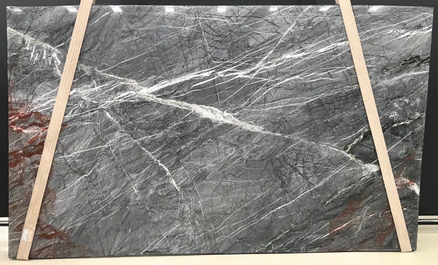 Crystos Quartzite slab with charcoal grey base, sharp white veining and rust and burgundy iron-oxide patches