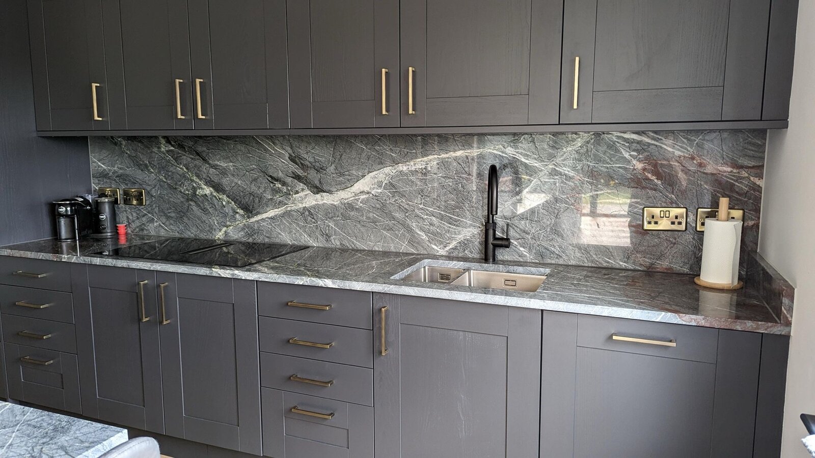 Kitchen with Crystos Quartzite worktops and a full-height splashback in grey shaker units